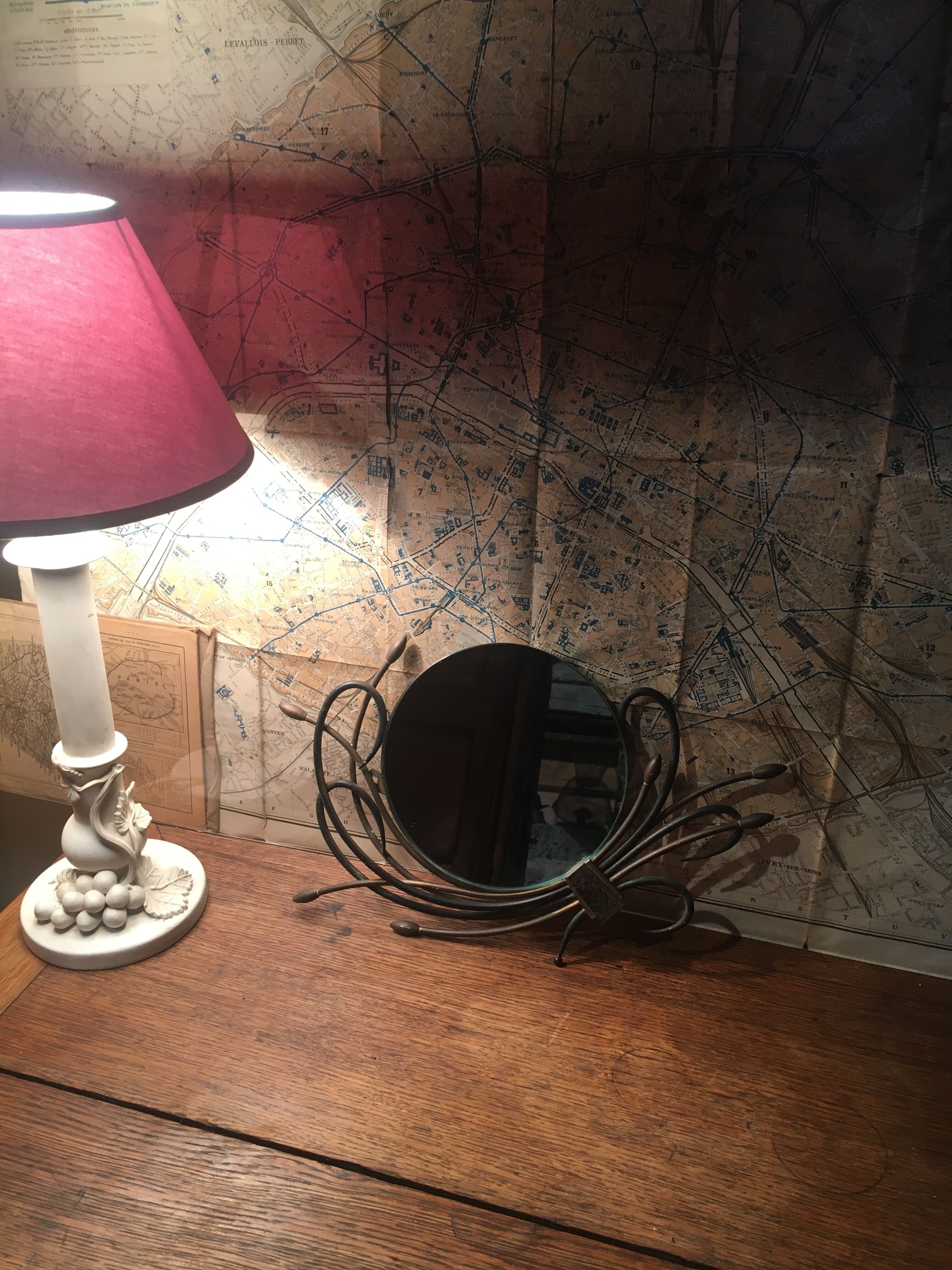 Round mirror surrounded by art deco style metal plants