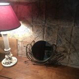 Round mirror surrounded by art deco style metal plants