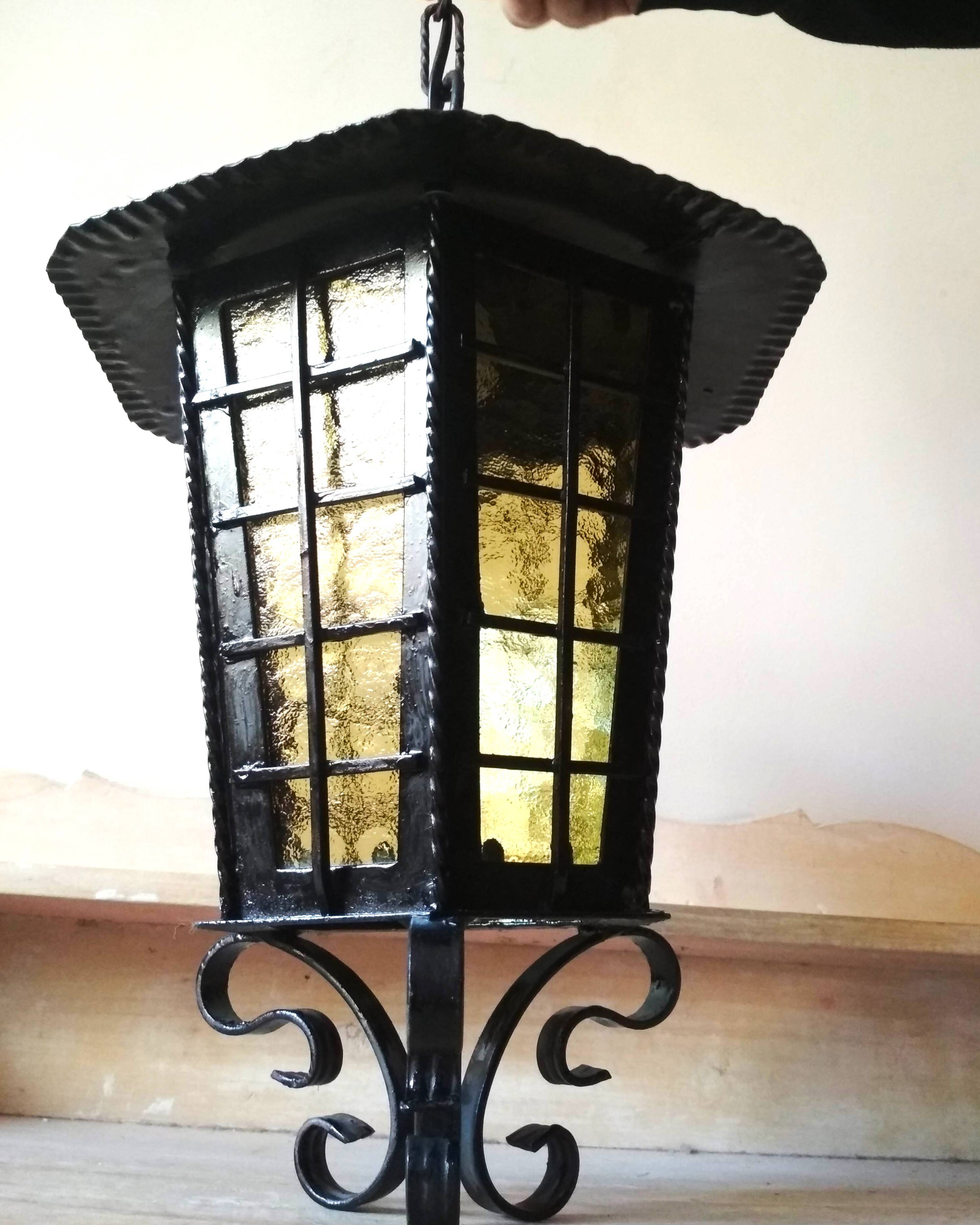 Large hanging lantern in wrought iron and opaque yellow-orange windows