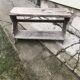 Small country bench in grey pine, rustic antique style with storage shelf.