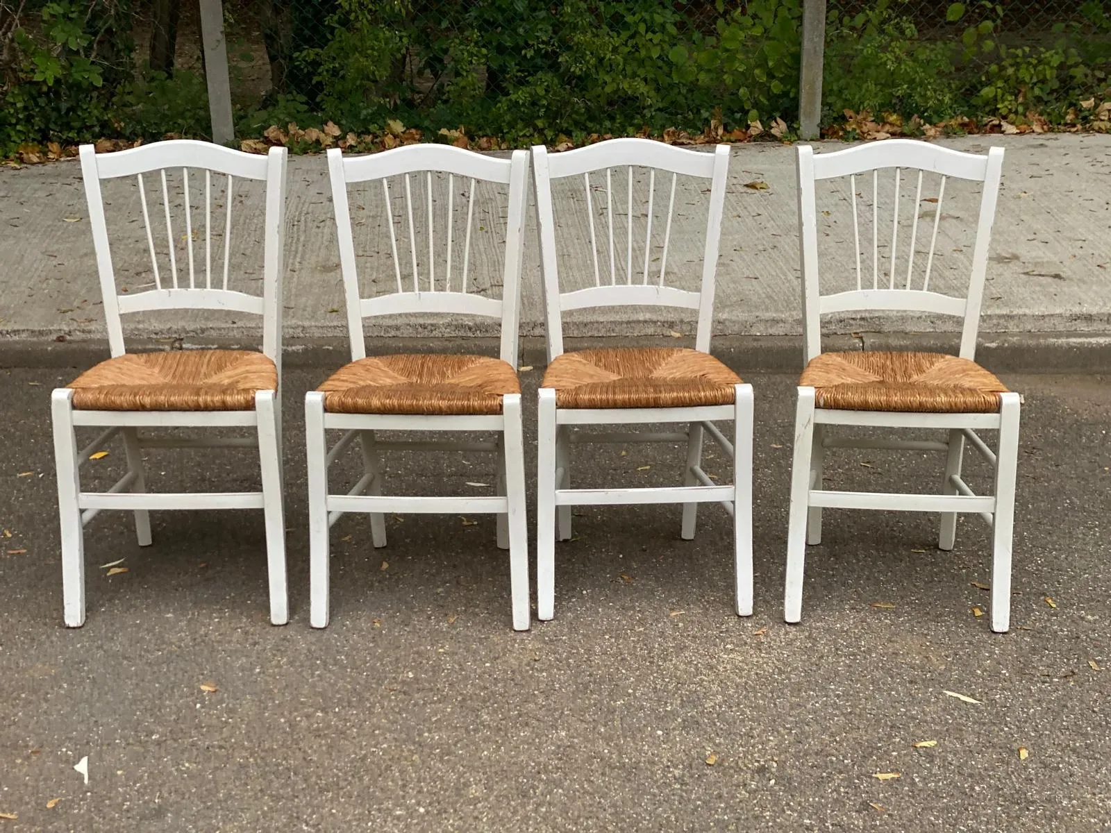 Set of 4 rustic white wooden chairs with straw seats.