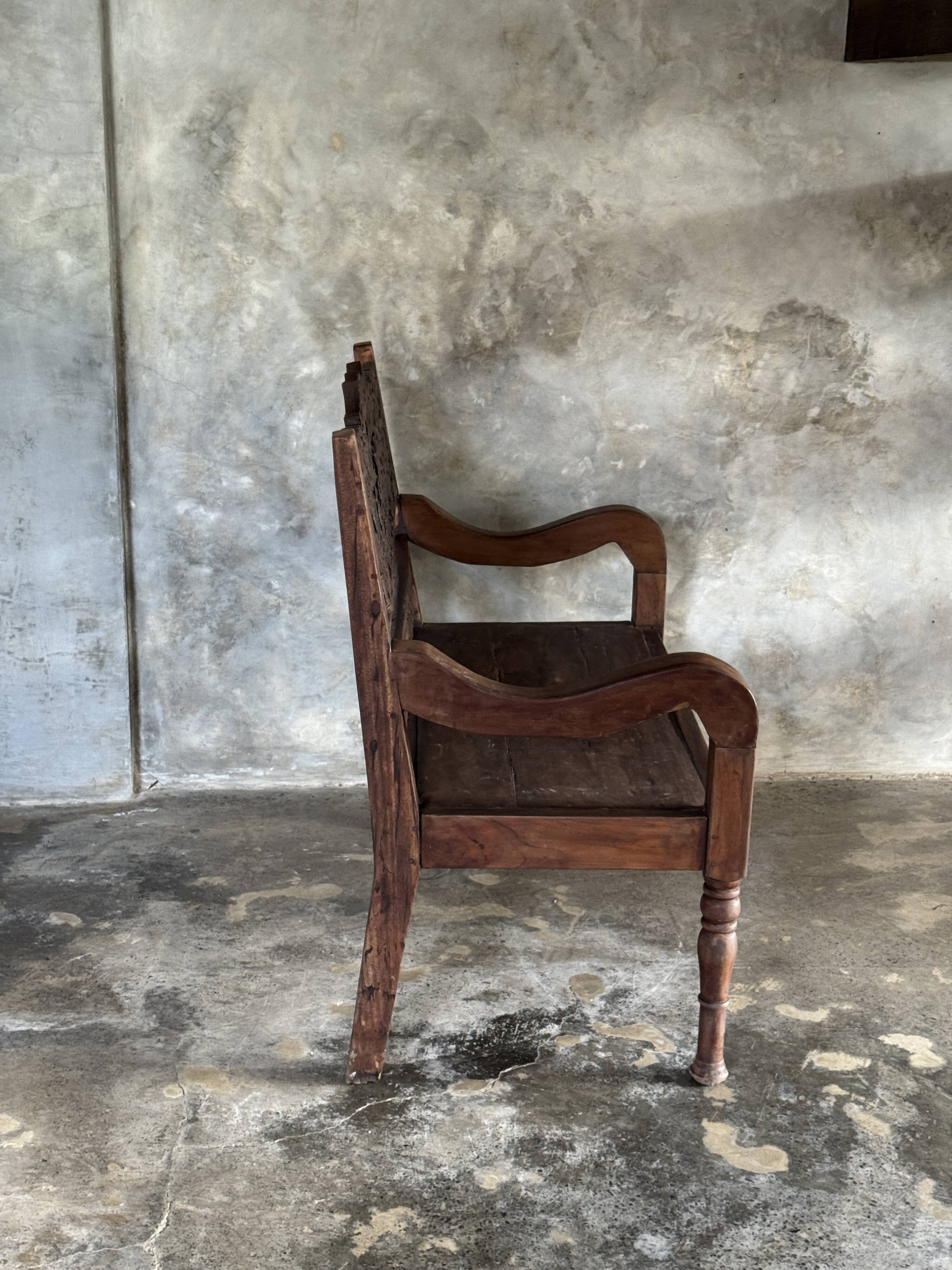 Small antique Indonesian bench in carved teak with plant and floral motifs.