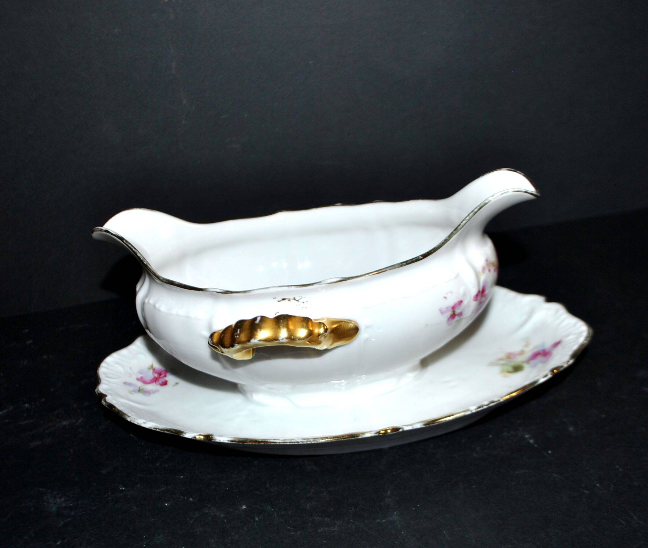 Vintage pouring sauce boat in floral porcelain with gilding.