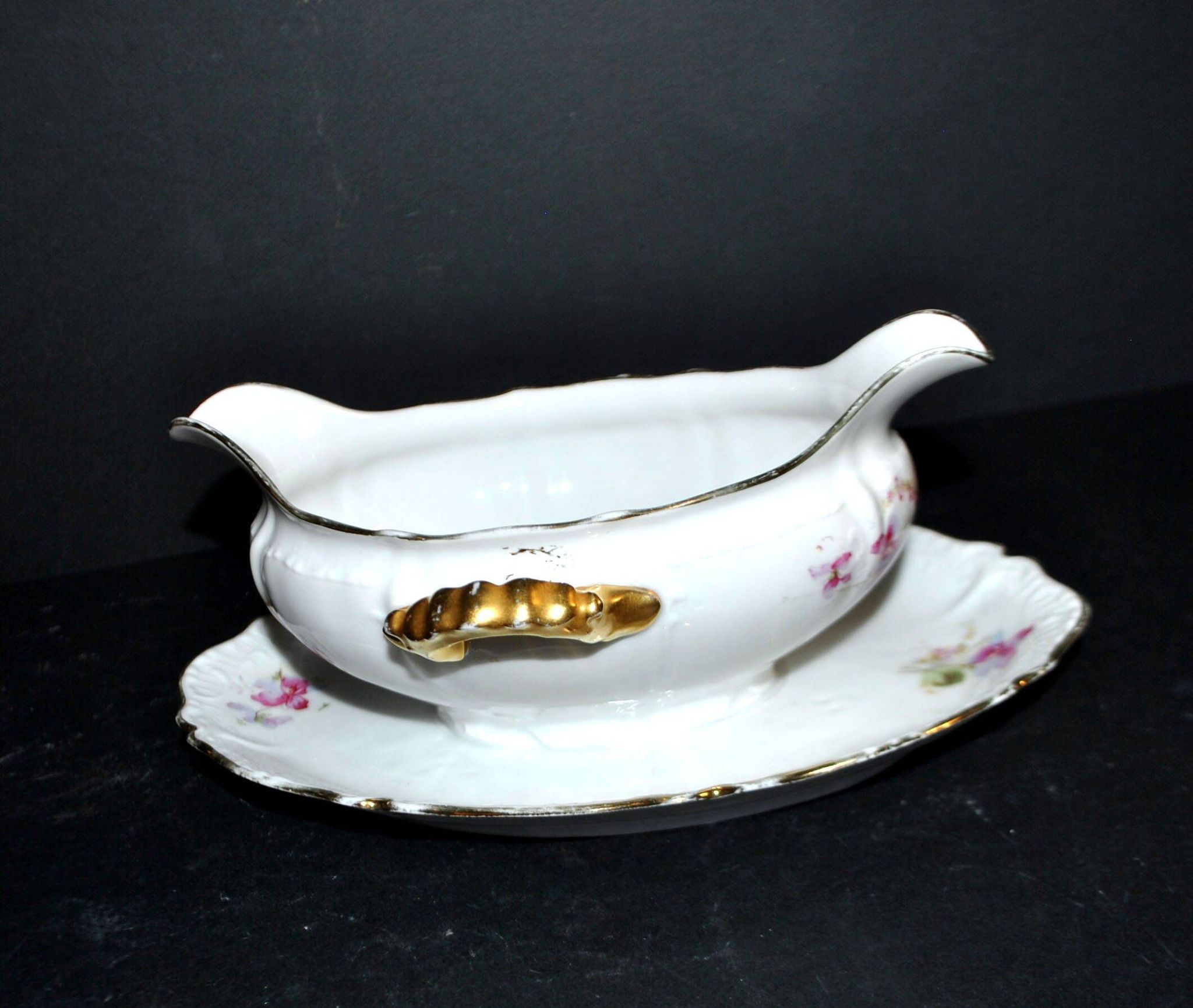 Vintage pouring sauce boat in floral porcelain with gilding.