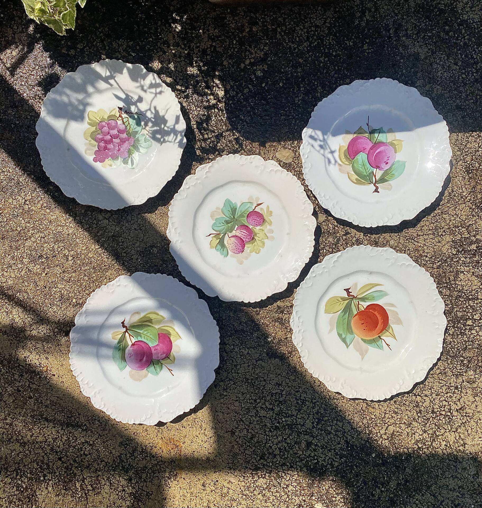 Antique plates from the late 19th century with scalloped edges and fruit decoration.