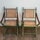 Paire de chaises safari pliantes façon faux-bambou patiné, dossiers et assises cannées et repose-bras en cuir