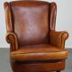 Fauteuil à oreilles en peau de mouton subtile en bon état sur roulettes avant en laiton