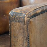 Fauteuil ancien en cuir de mouton sur roulettes et patiné