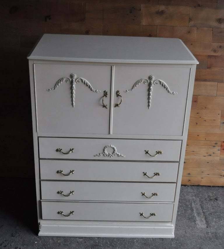 Mid-century wooden dresser painted in cream white, with 2 doors and 4 drawers, brass fittings.