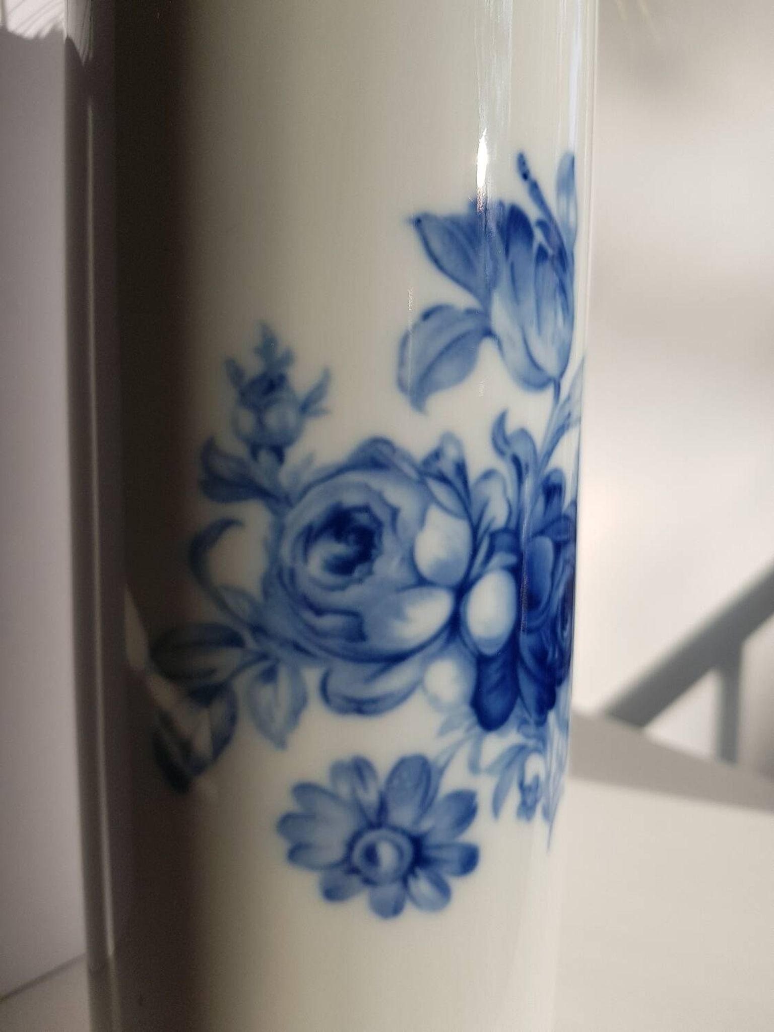 White porcelain vase from Limoges with blue decoration and gold rim.