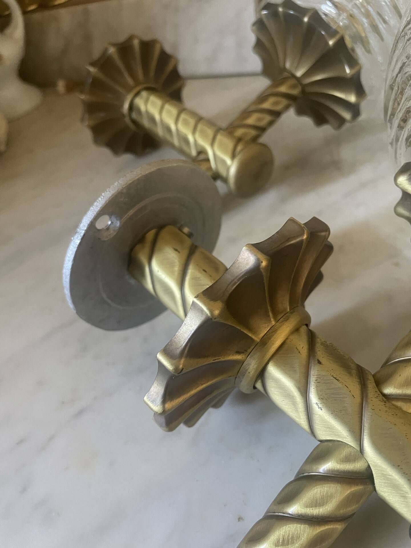 Pair of neoclassical wall sconces in twisted brass and ribbed glass.