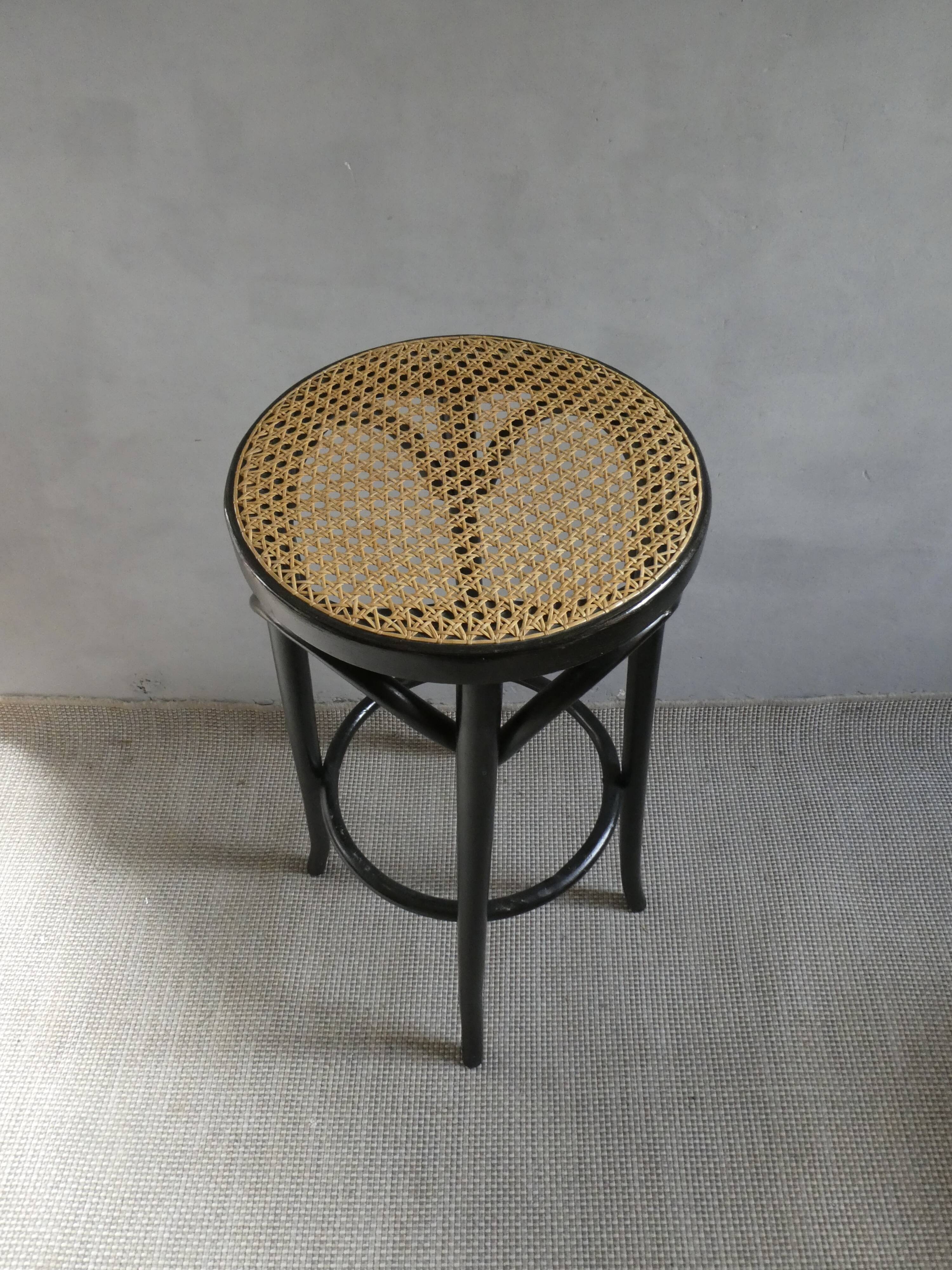 Curved wooden bar stool with a caned seat.