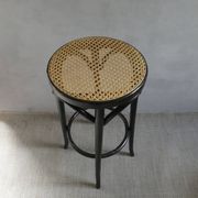 Curved wooden bar stool with a caned seat.