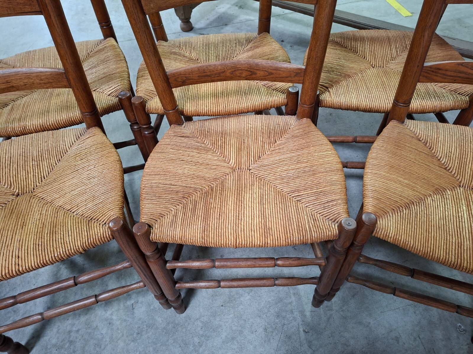 Set of six rustic chairs in natural wood with straw seats.