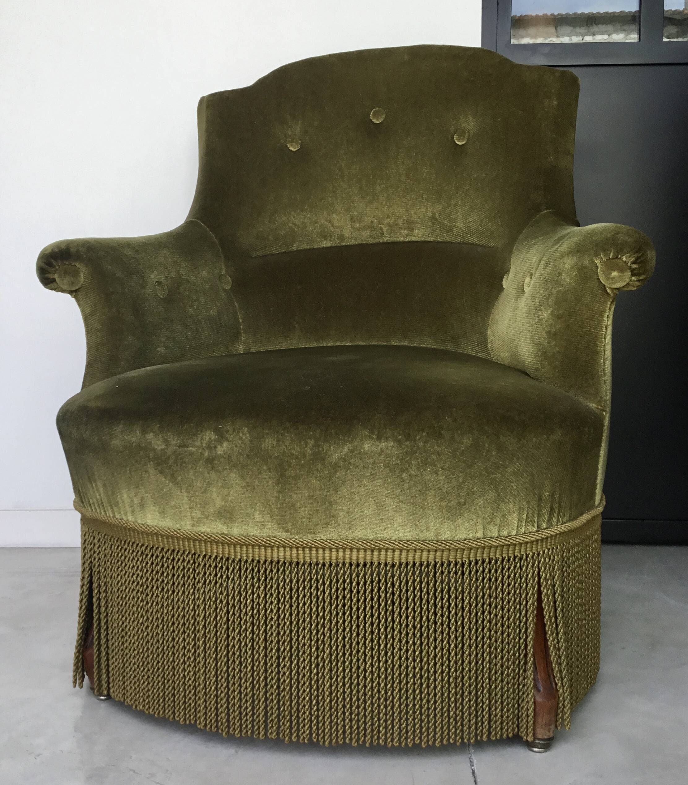 Olive green toad armchair with smooth velvet fringes.