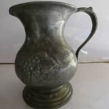 pewter pitcher with handle and bunch of grapes on the pot