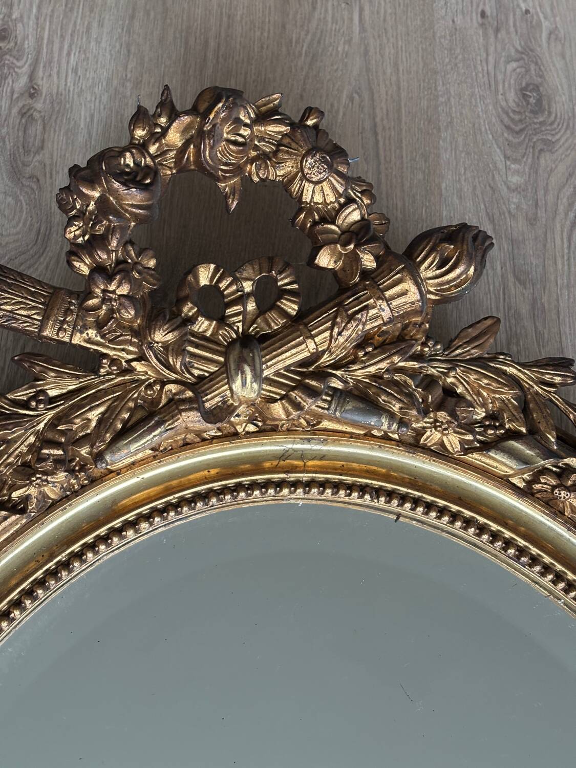 19th century oval gilded mirror, torch & quiver 106cm