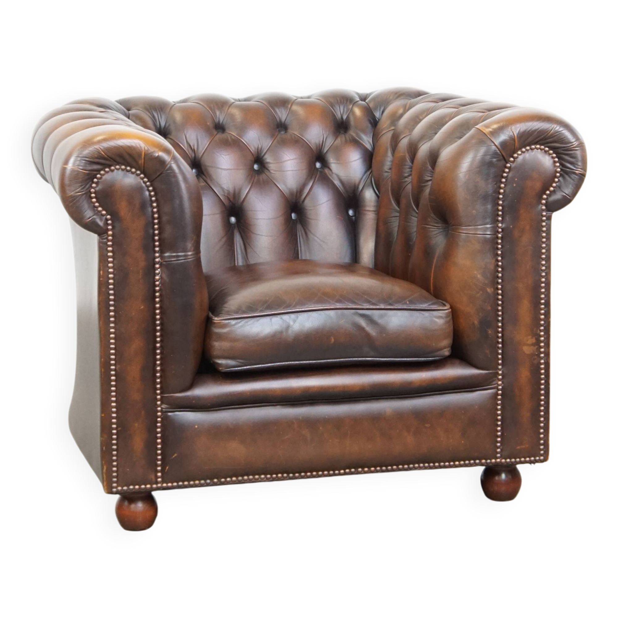 Cowhide English Chesterfield armchair with ball legs and timeless finish