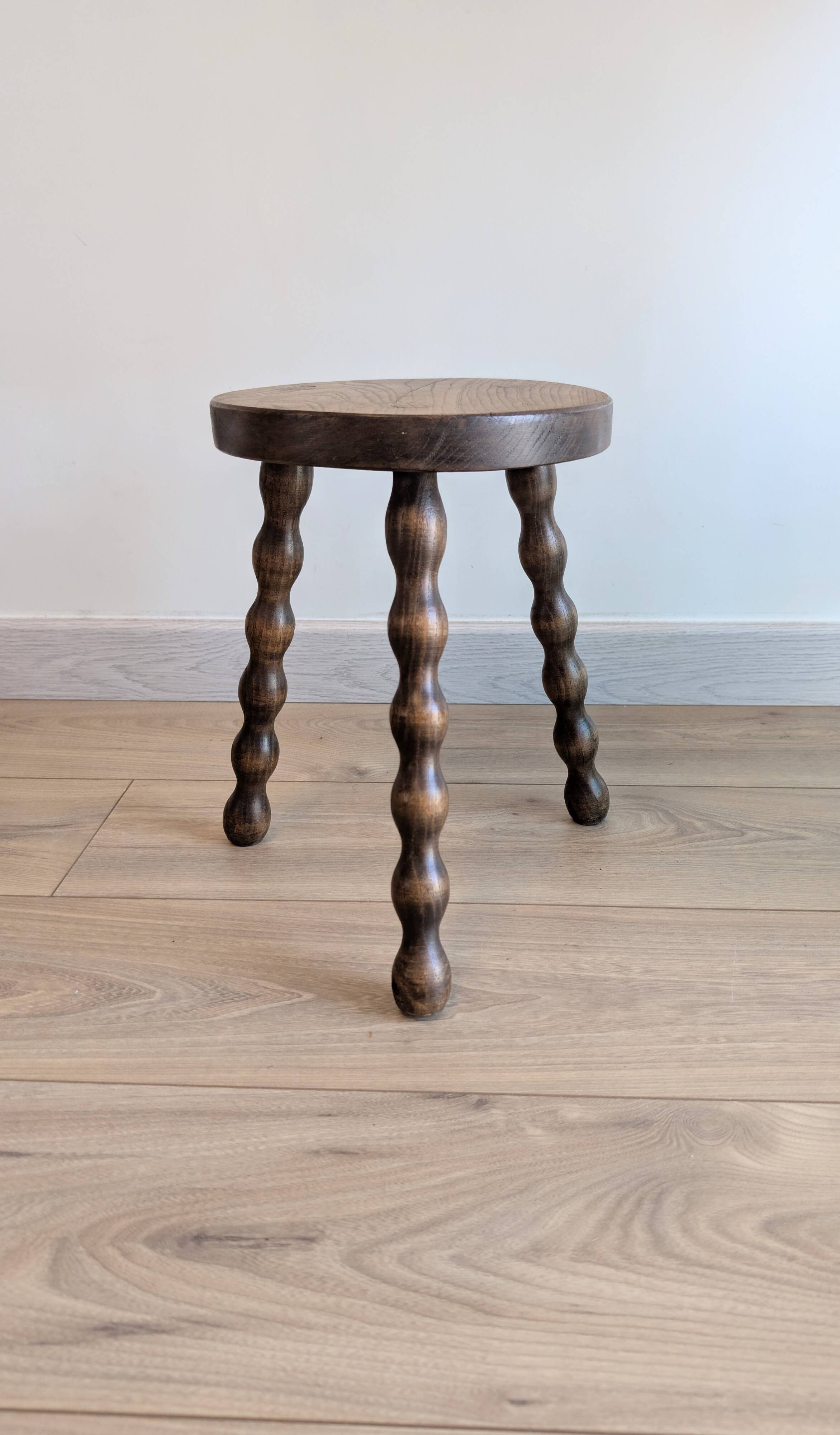 Small wooden tripod stool with turned legs, country style.