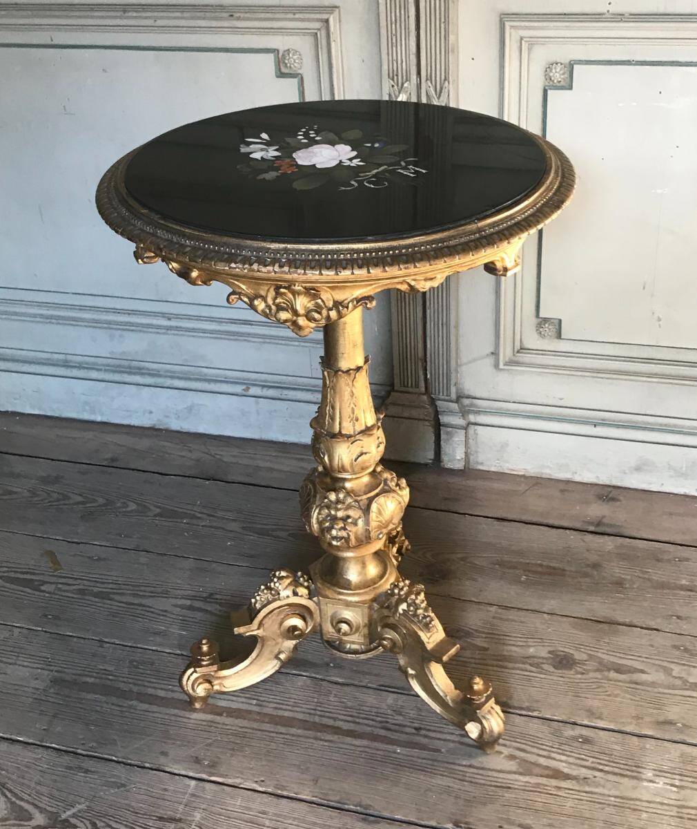 A gilded carved wooden pedestal table with a marble marquetry top