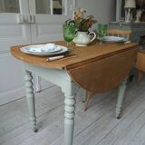 Walnut table with raised flaps, base on verdigris casters.