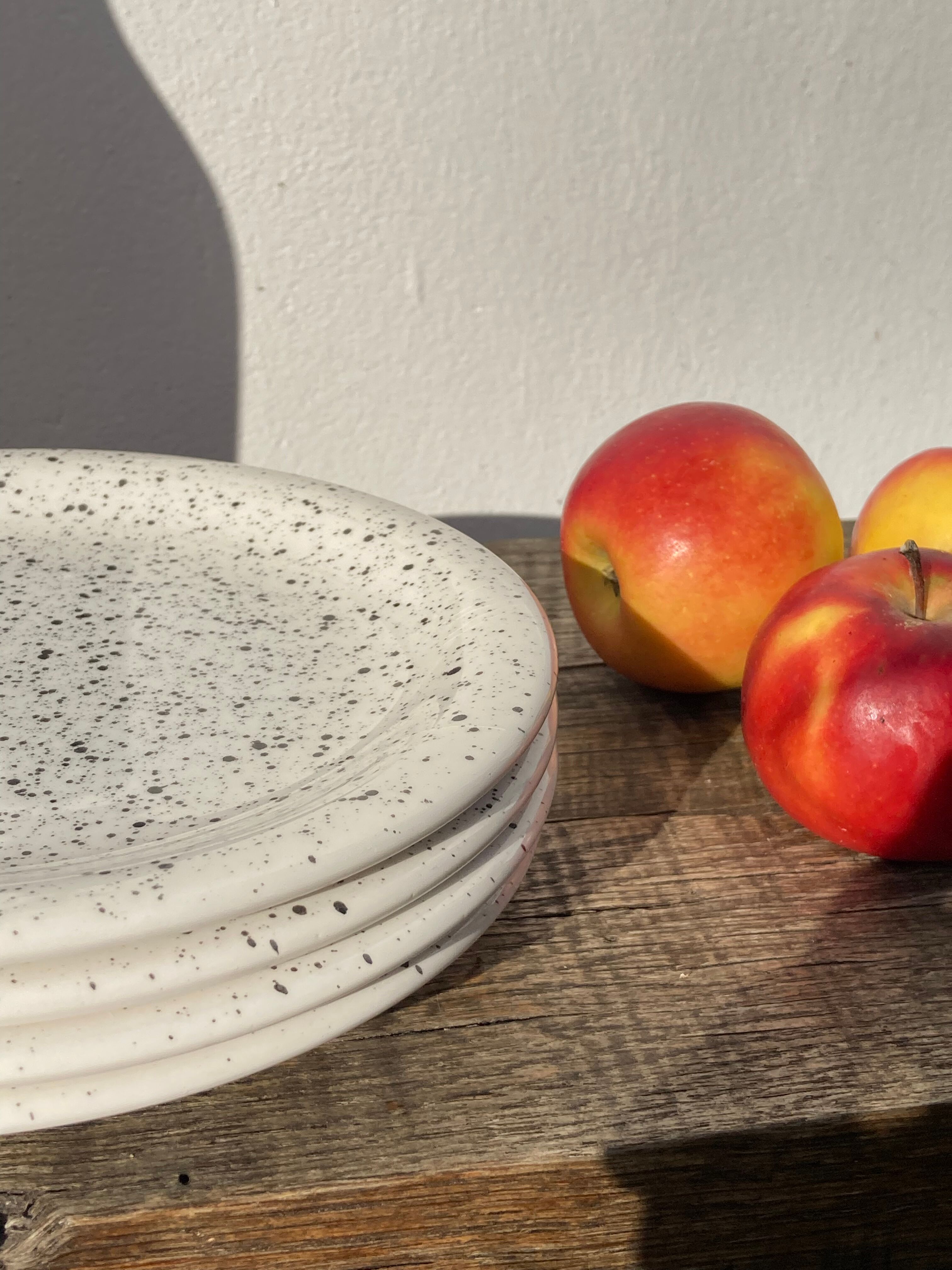 4 black speckled dessert plates on a vintage white background