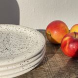 4 black speckled dessert plates on a vintage white background