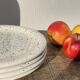 4 black speckled dessert plates on a vintage white background
