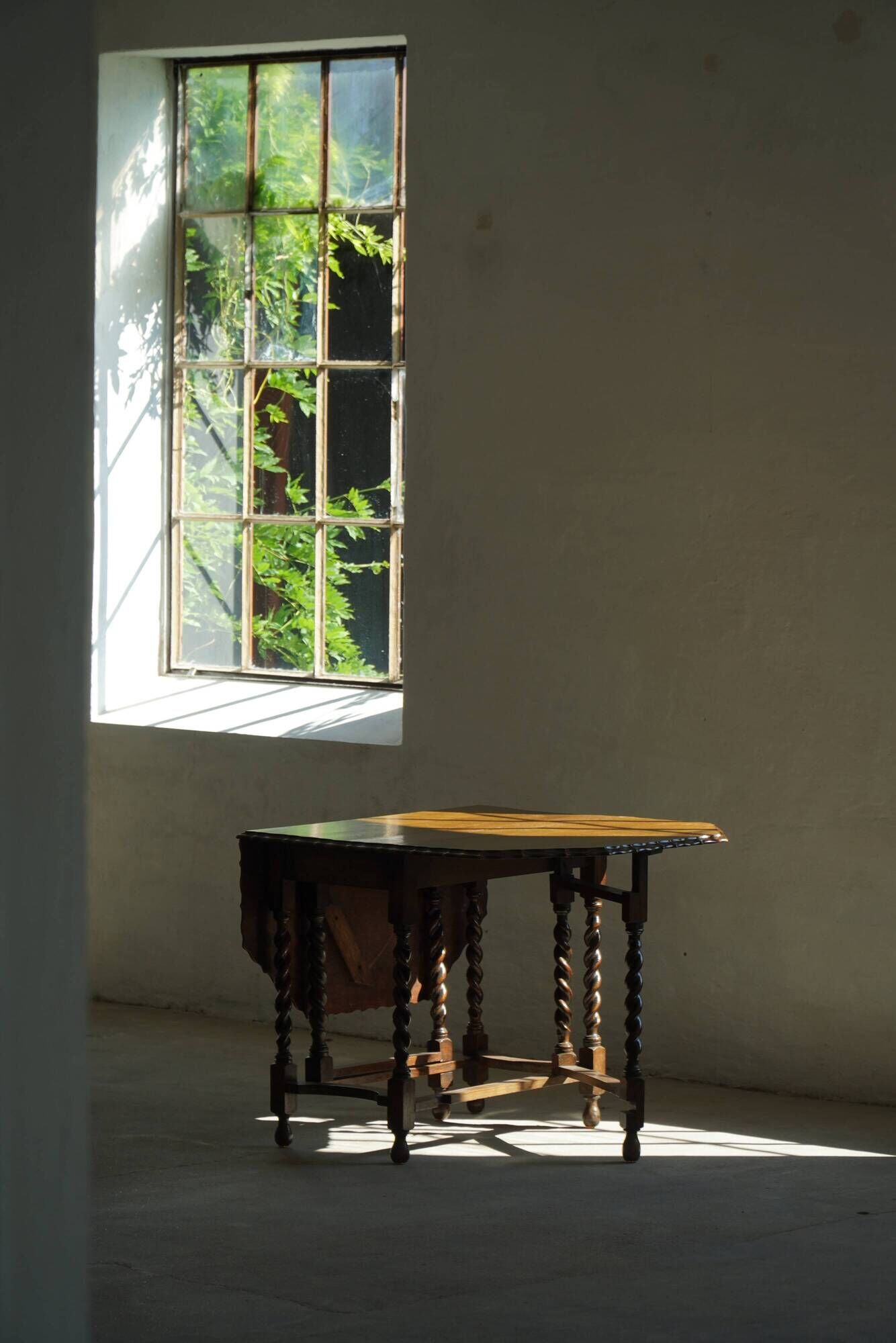 Antique baroque dining table in oak, with folding legs and drop leaves, featuring spiral "barley twist" legs, from the 1920s.