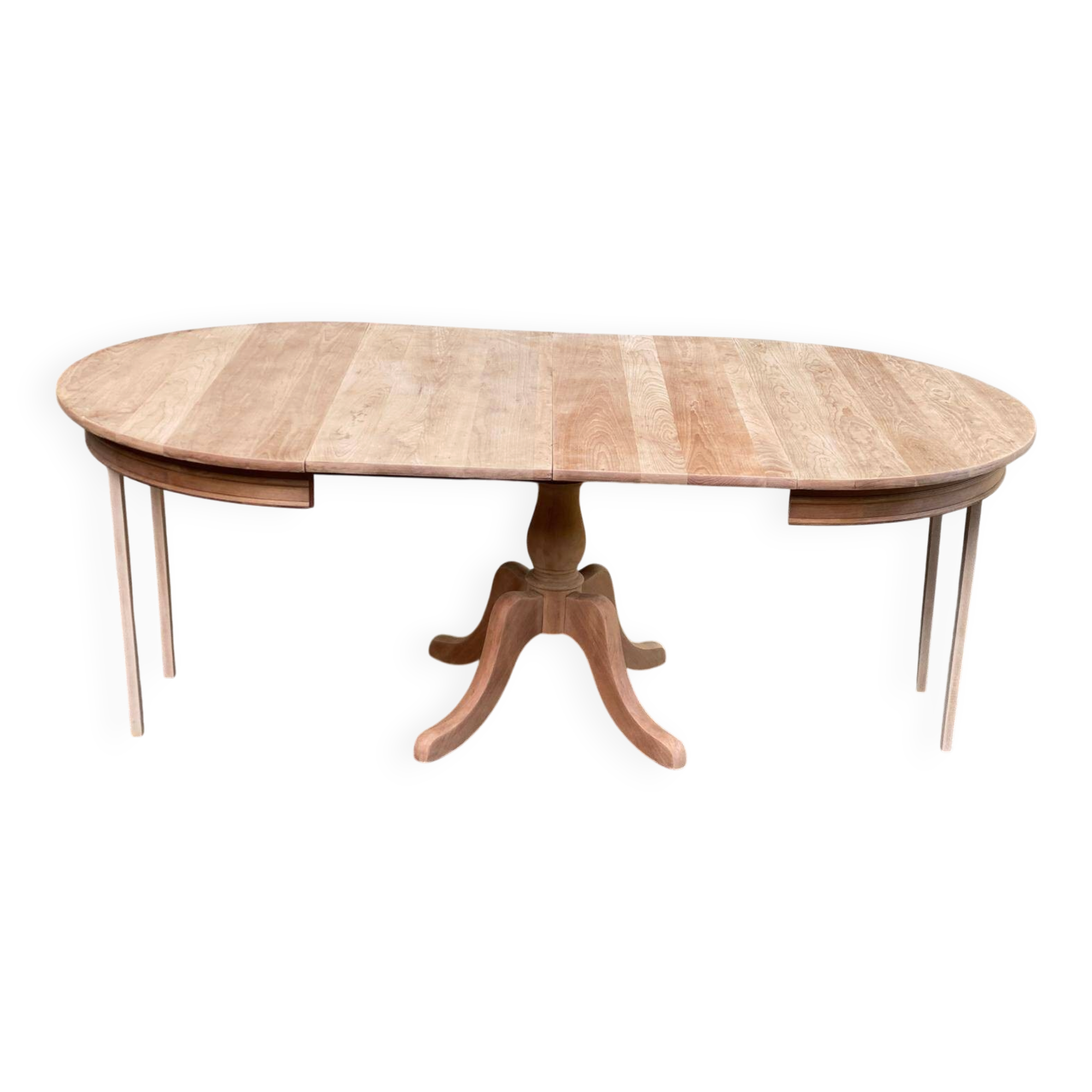 Large extendable round dining table stripped in solid cherry wood with a central leg.