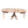 Large extendable round dining table stripped in solid cherry wood with a central leg.
