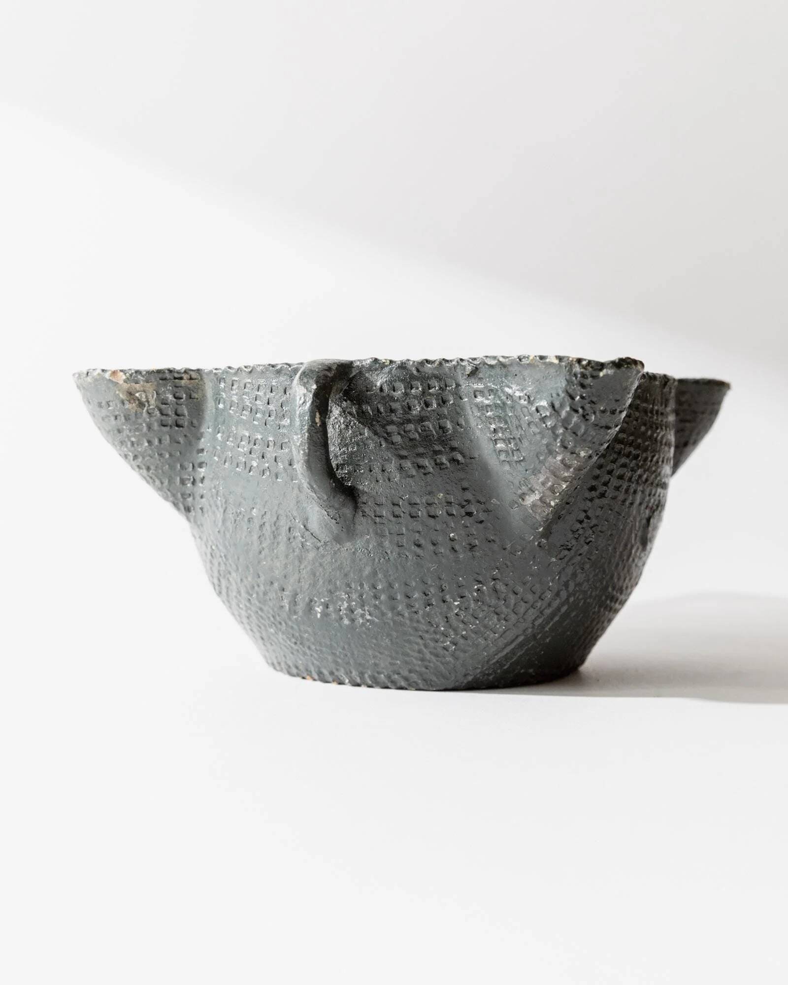 Vintage ceramic ashtray from the 1960s, black, hand-sculpted texture, organic shape.