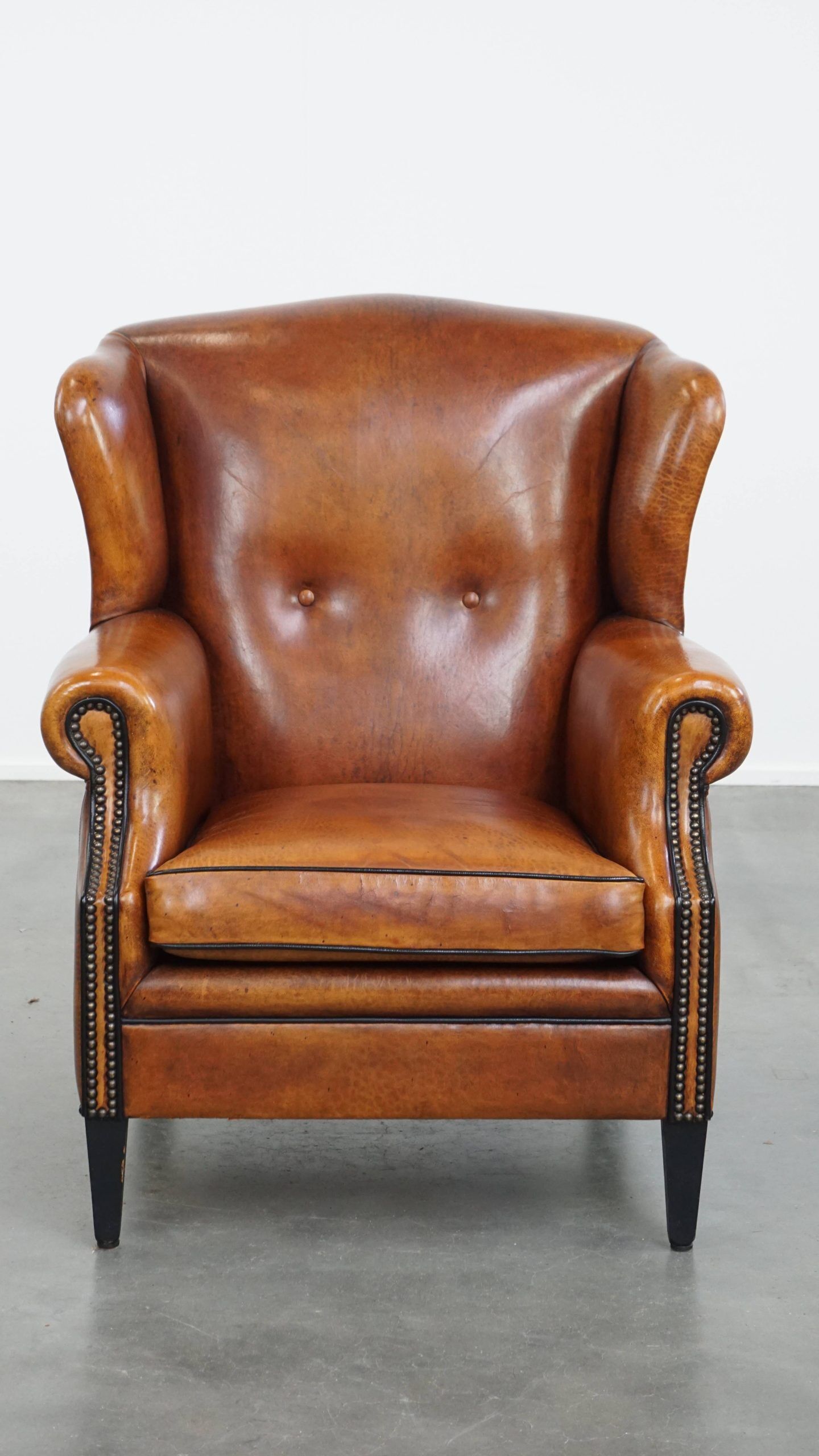 Sheepskin wingback armchair with stitching and black piping