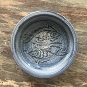 Glazed blue ceramic bowl with stylised fish decoration.