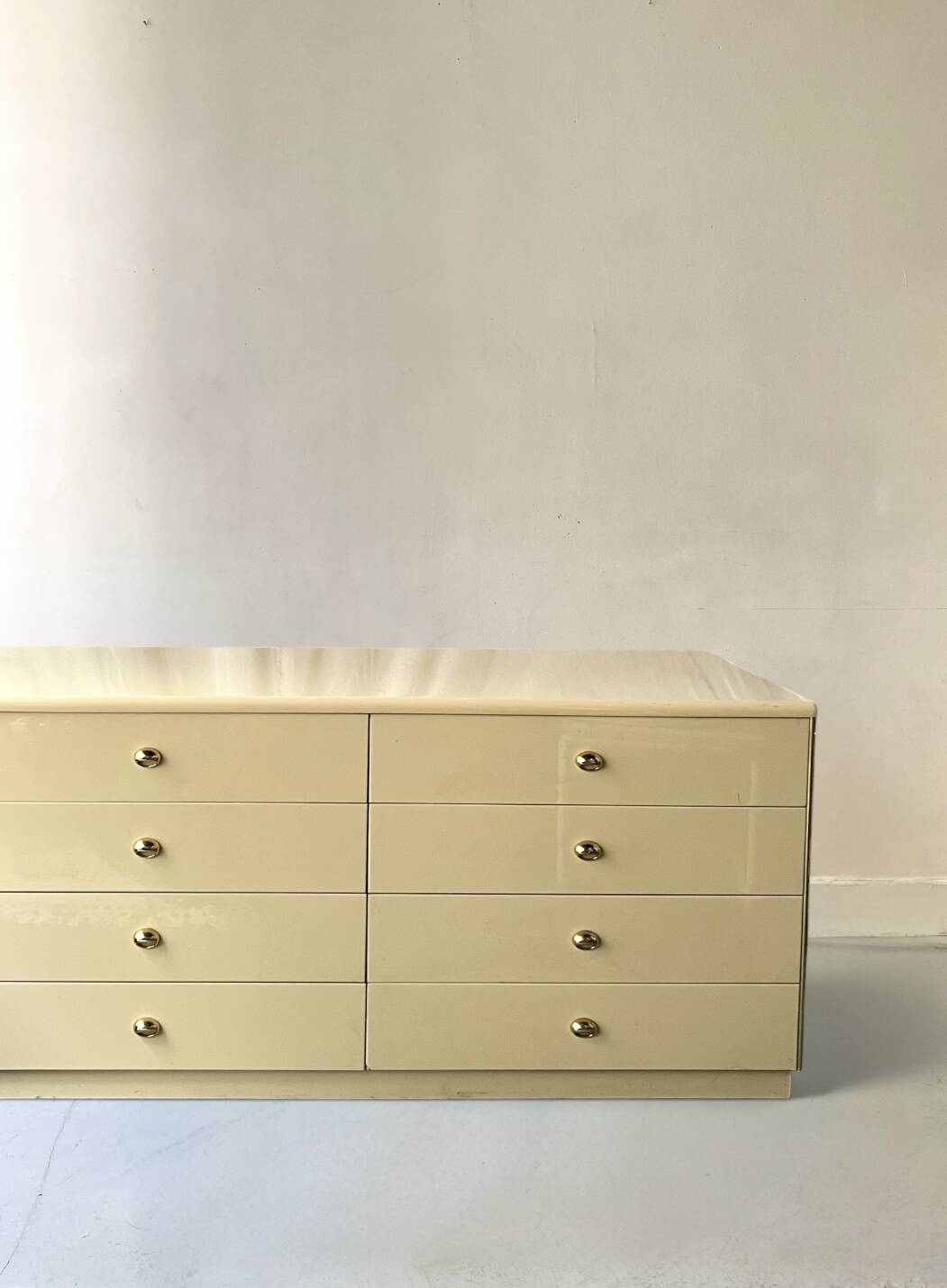 Commode type sideboard with 8 drawers, ivory lacquer and brass details, 1970s design.