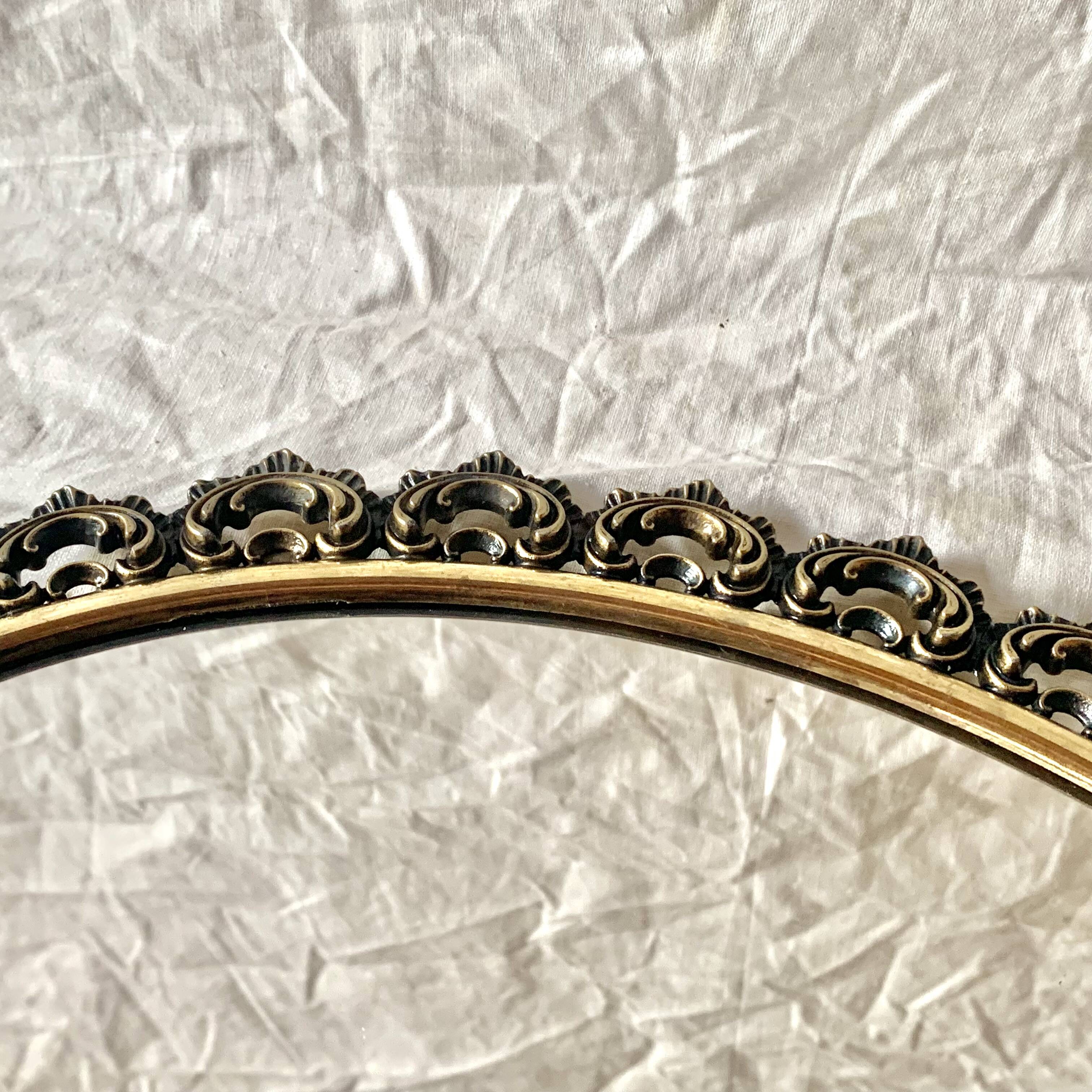 Old oval wall mirror in gilded brass