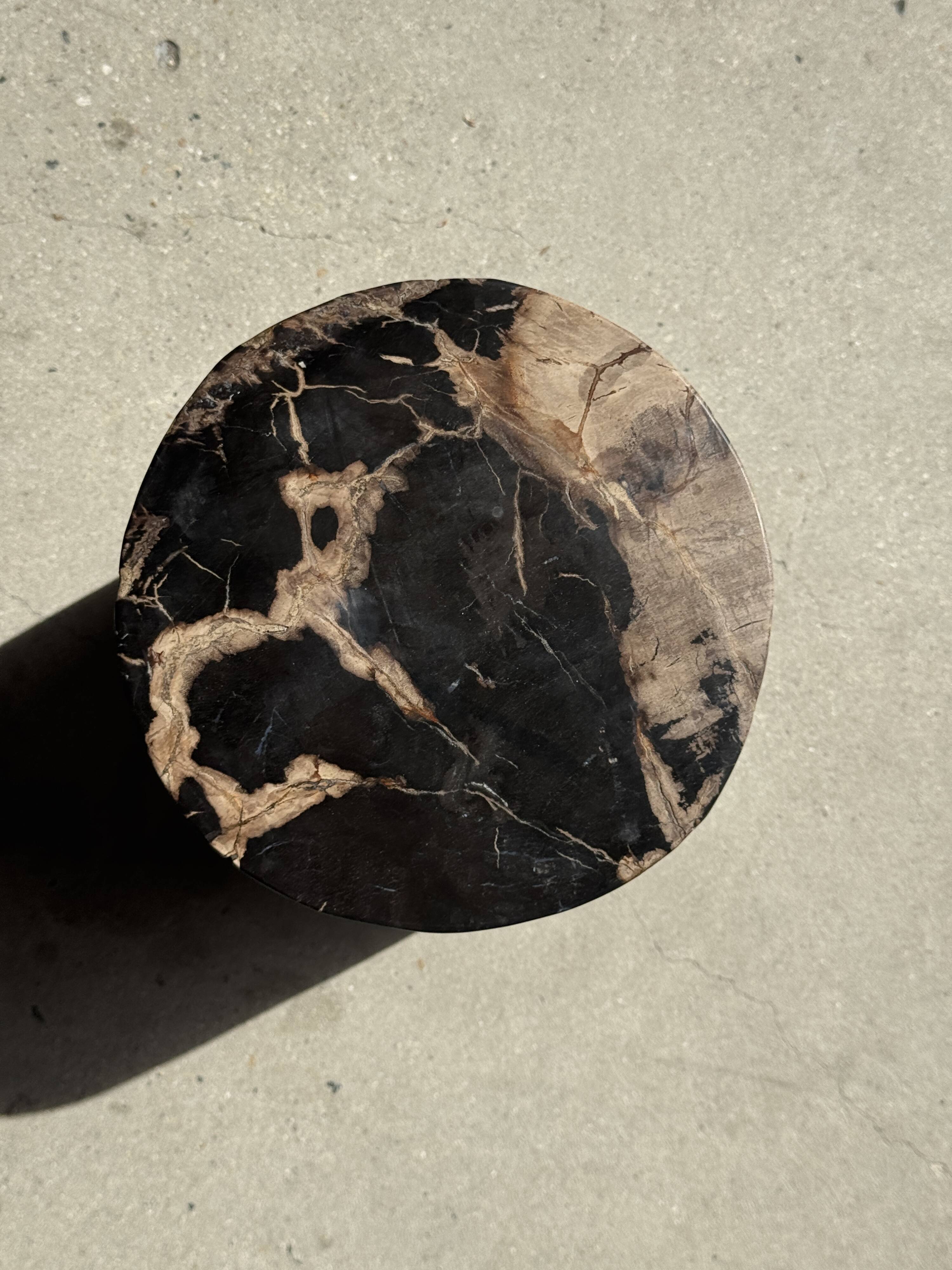 Black petrified wood side table with beige stripes and a semicircular shape.