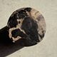 Black petrified wood side table with beige stripes and a semicircular shape.