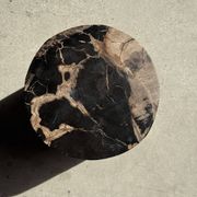 Black petrified wood side table with beige stripes and a semicircular shape.