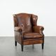 Sheepskin wingback armchair with decorative nails and black piping