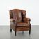 Sheepskin wingback armchair with decorative nails and black piping