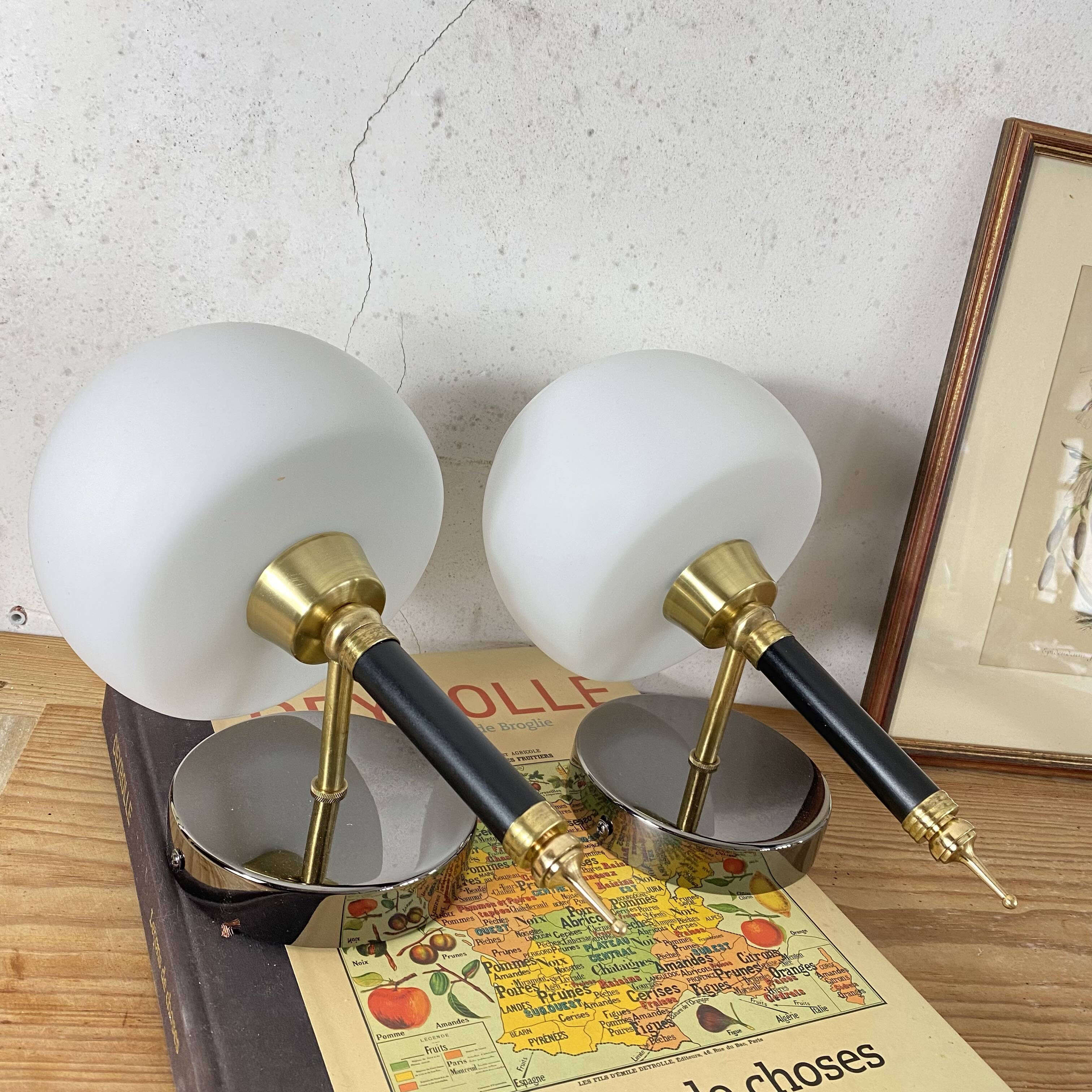 Pair of wall sconces with brass torch and white glass globe.
