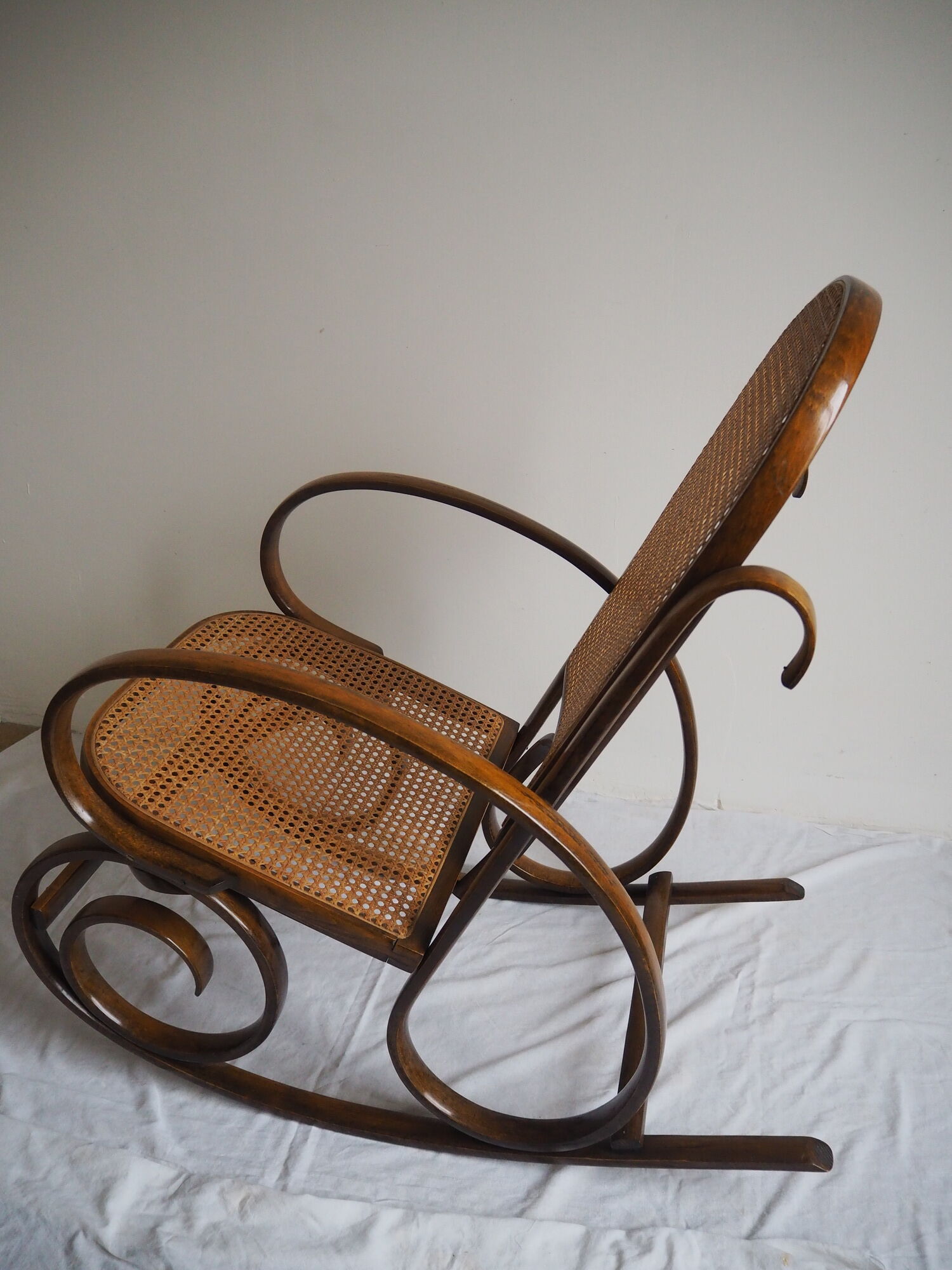 Rocking-chair en bois teinté et assise cannée