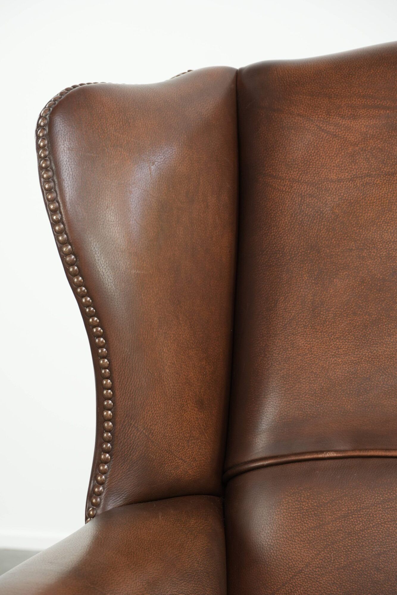 Cowhide wingback armchair in English style finished with decorative nails