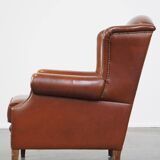 Correct, comfortable, luxurious English-style wingback armchair made of cognac-colored cow leather