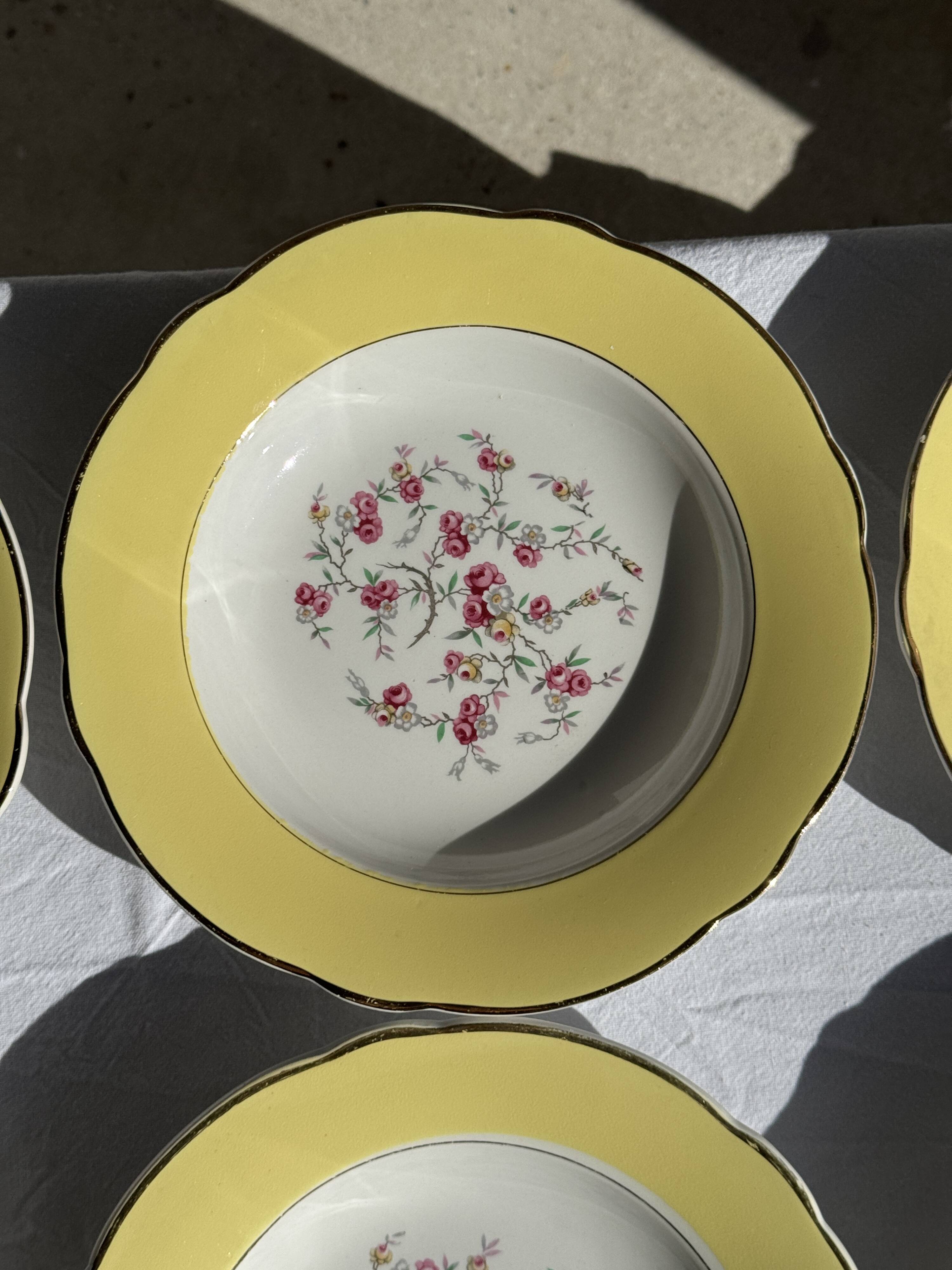 Set of 9 large vintage yellow deep plates with pink flowers and a gold rim.