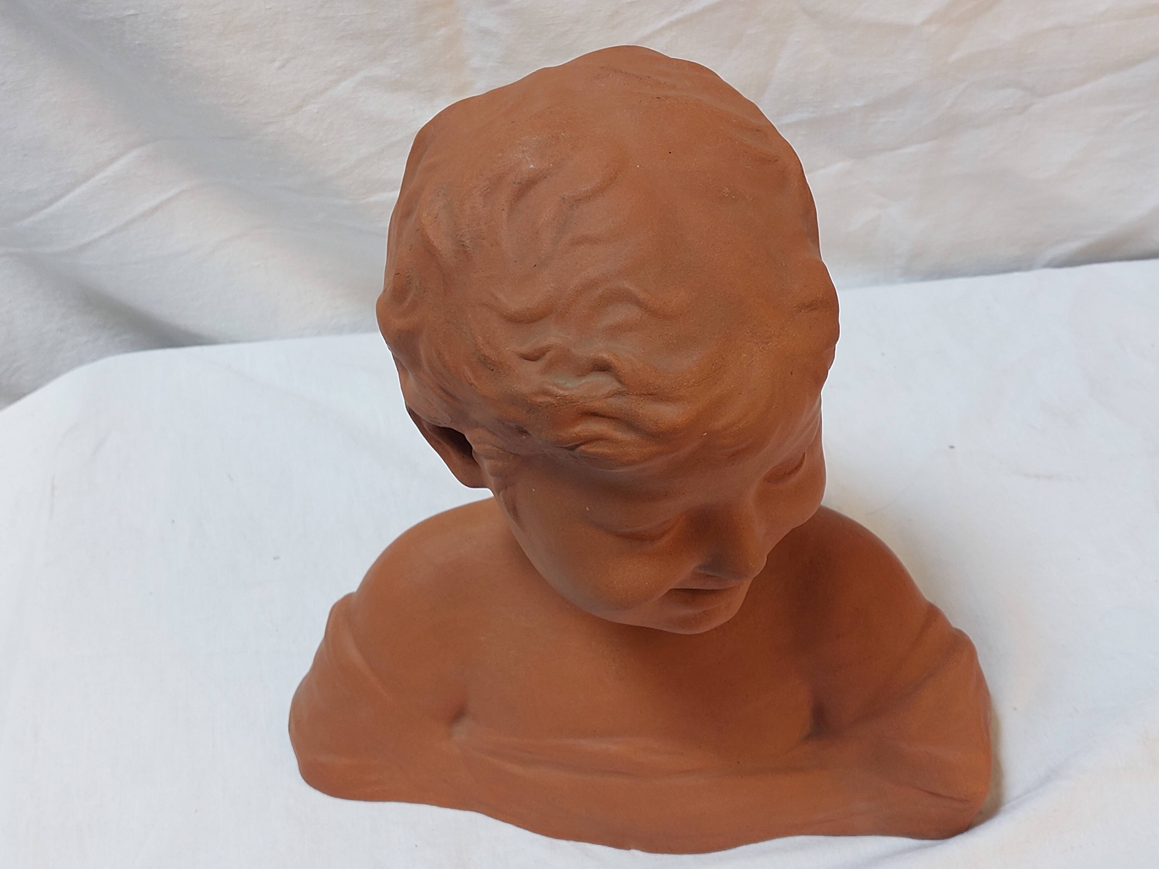 Terracotta bust of a smiling little boy.