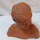 Terracotta bust of a smiling little boy.