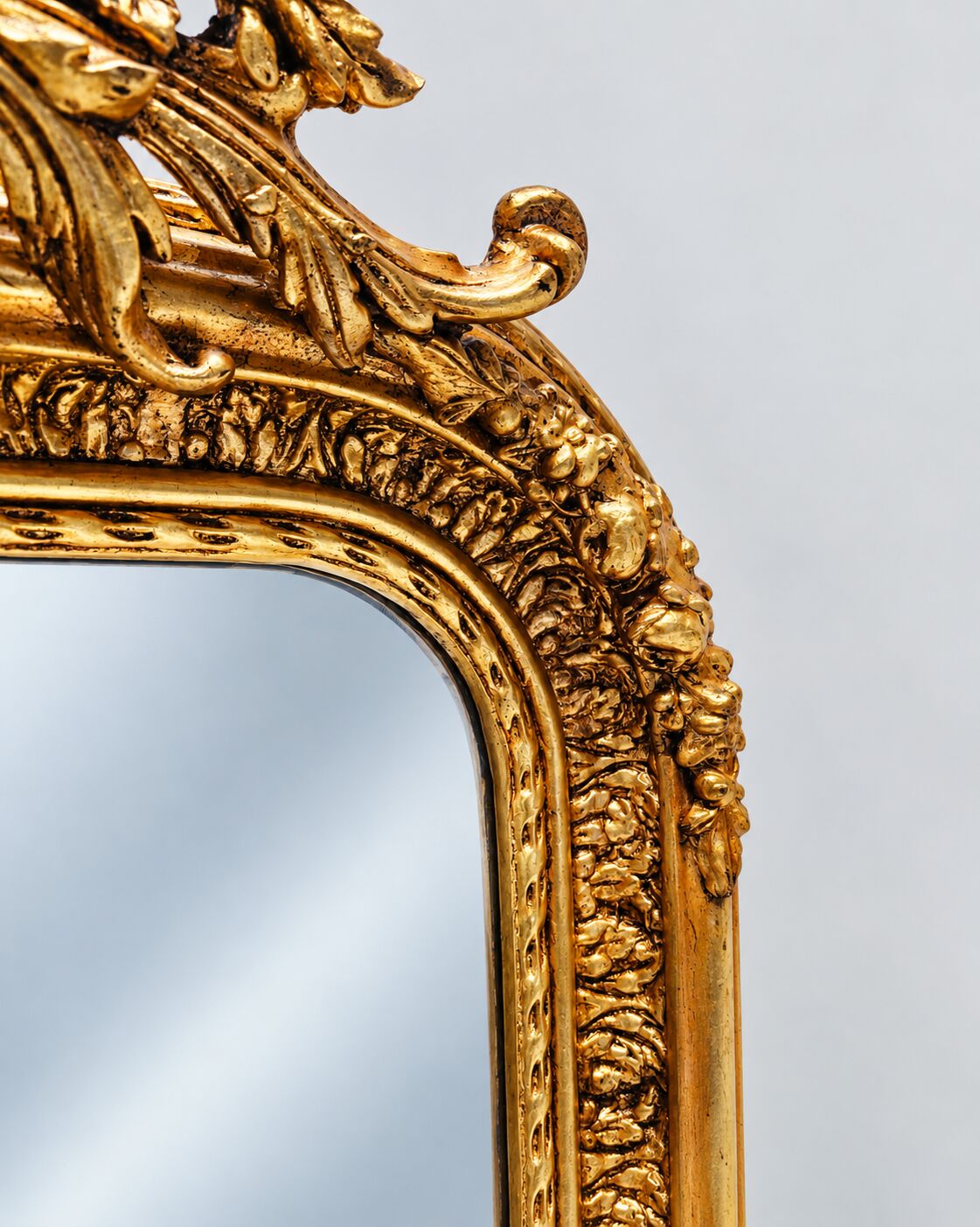 Grand miroir baroque en or avec un crête orné.