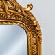 Grand miroir baroque en or avec un crête orné.